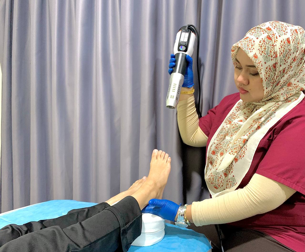 Terapis merawat kaki pesakit dengan peralatan terapi